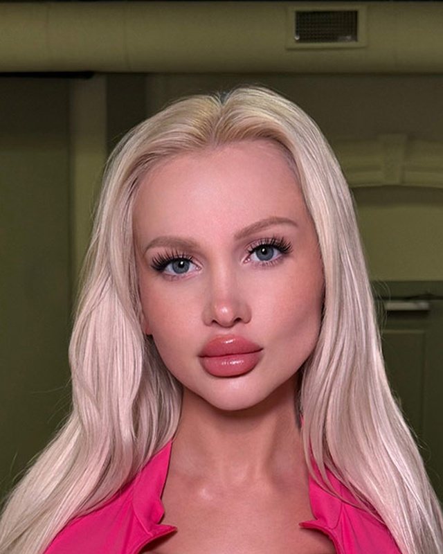 Bimbo aesthetic portrait in a hot pink top with long platinum blonde hair.