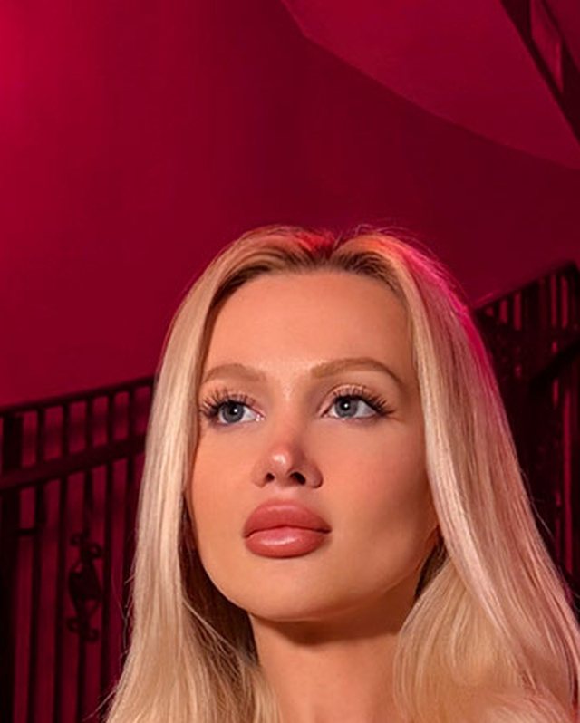 Bimbo aesthetic portrait: platinum blonde hair, glossy lip and soft pink lighting.