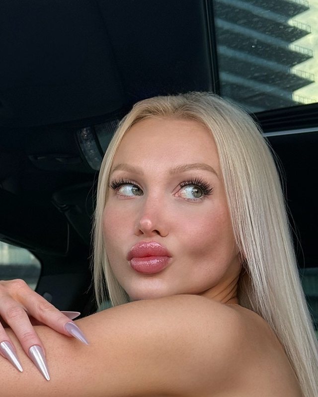 Soft-lit bimbo aesthetic portrait with platinum hair and a glossy rose lip.