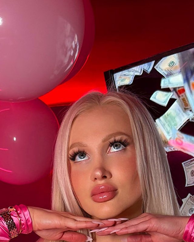Hyper-feminine bimbo style: hot pink monochrome outfit with satin texture and long platinum hair.